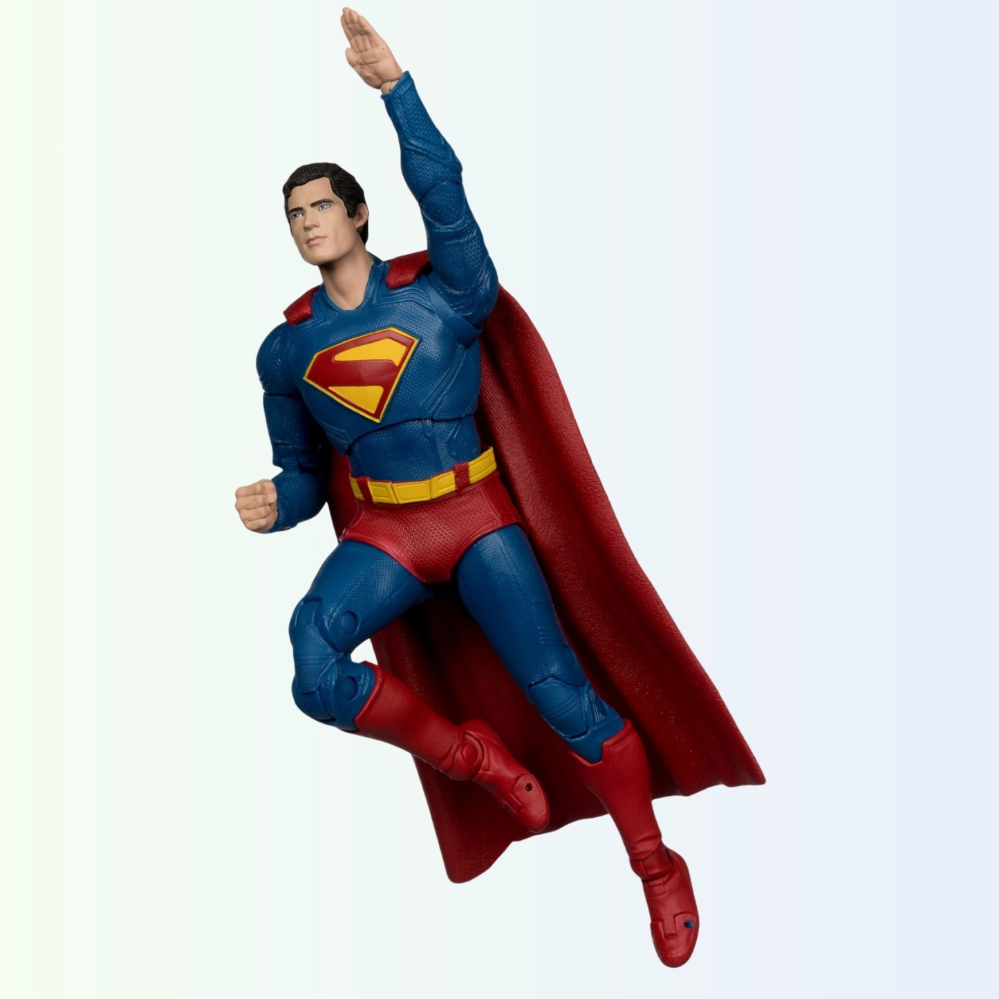 Dynamic flying pose of Superman action figure with one arm raised and cape flowing