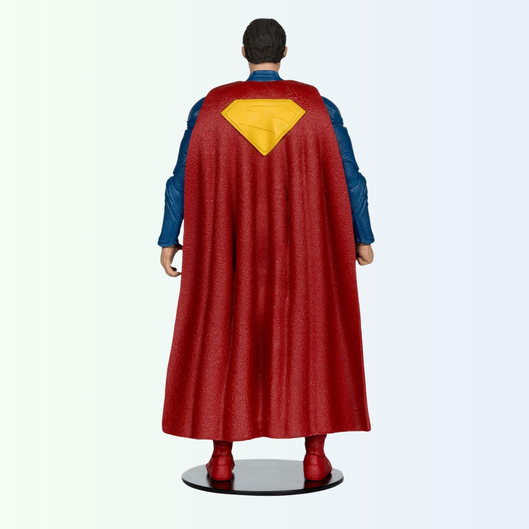 Rear view of Superman action figure showing cape texture and yellow 'S' symbol