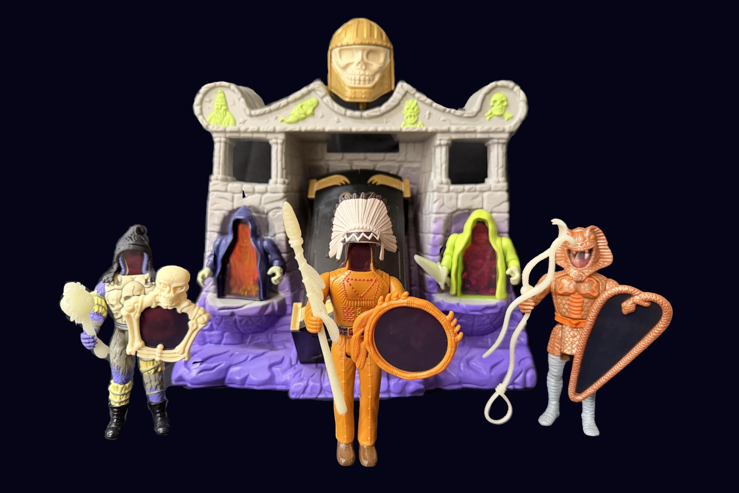 Tomb of Doom playset with three Super Naturals figures standing in front, including Skull with skull shield, Eagle-Eye with oval shield, and Snakebite with heart-shaped shield