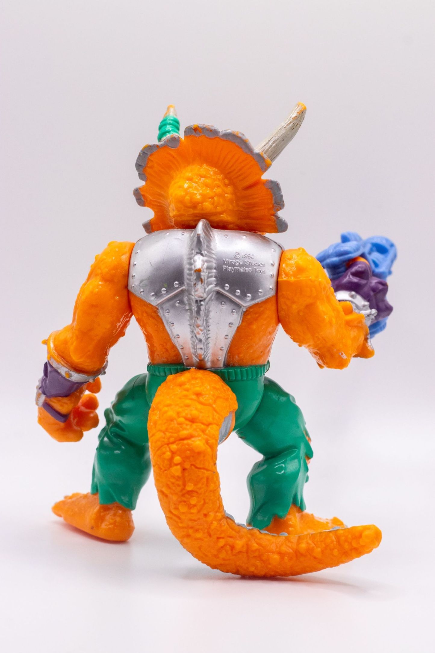 Back view of Triceraton action figure showing sculpted tail and silver back plate