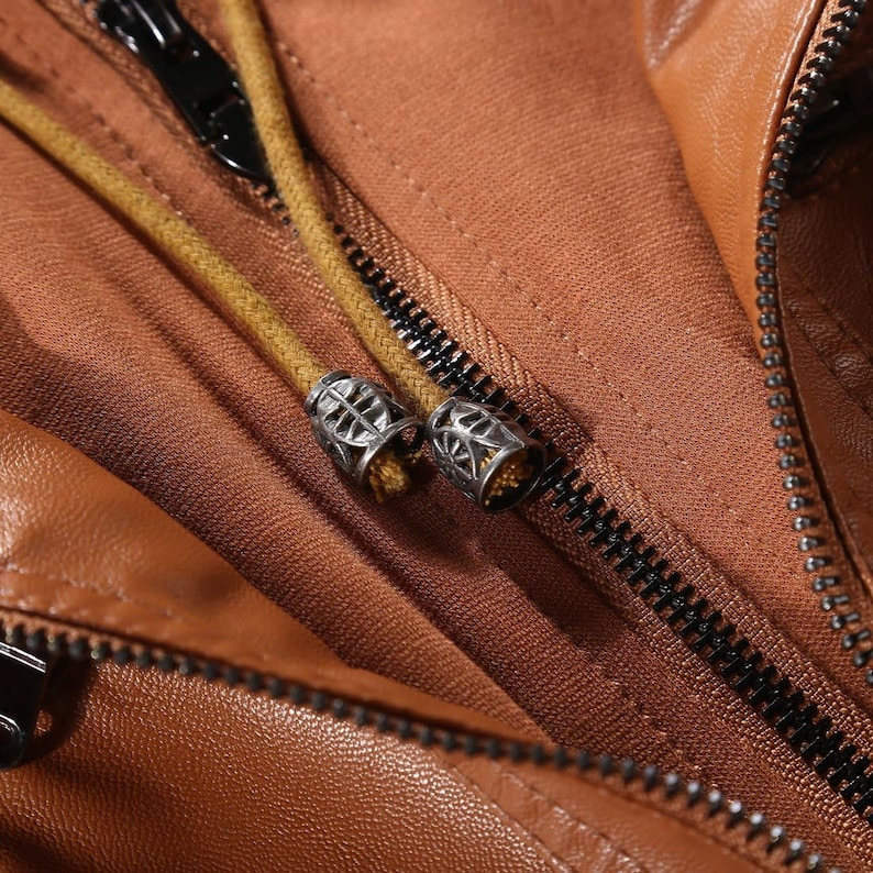 May include: A close-up of a brown leather jacket zipper with a yellow drawstring and silver metal zipper pulls.