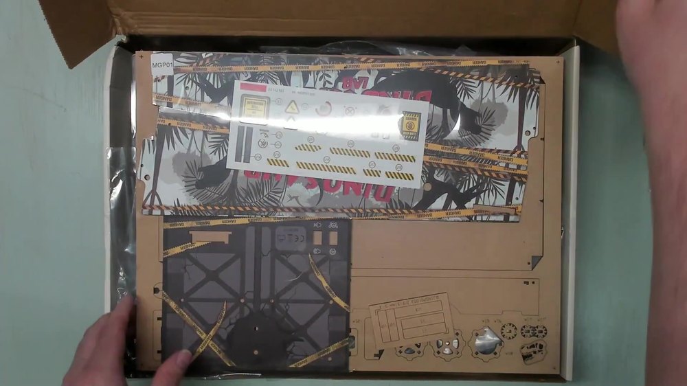 Opened Dinosaur Lab Pinball box showing sticker sheets, panels, and bagged parts