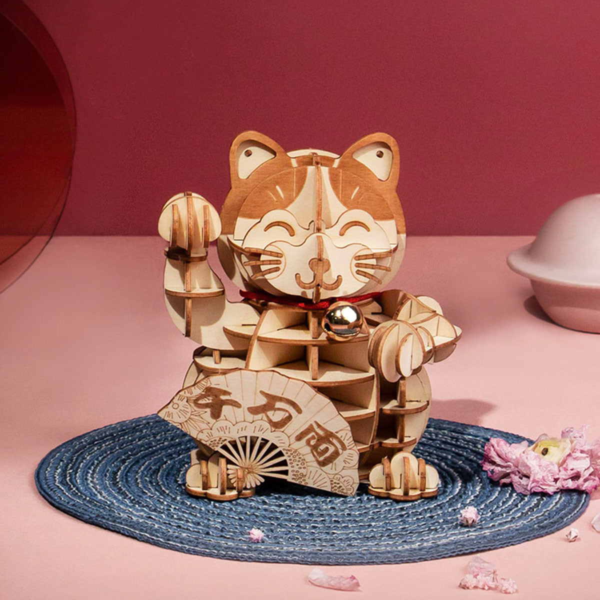 Rolife Plutus Cat TG303 wooden lucky cat with raised paw, decorative fan and bell, displayed on a dusky pink background