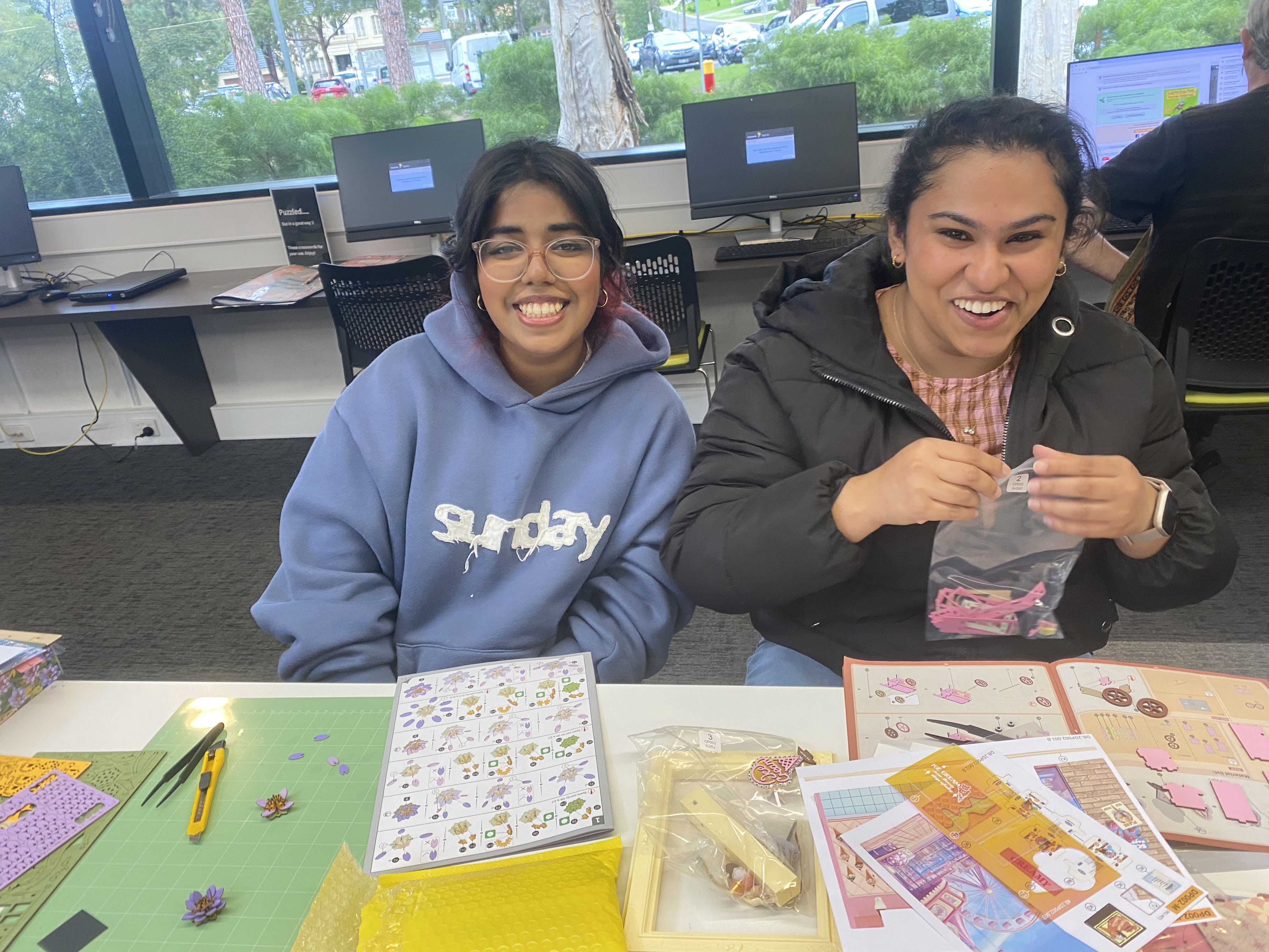 Two smiling Melbourne meetup participants working on miniature kits together
