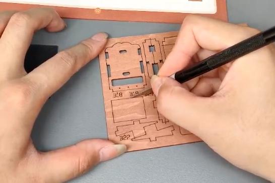 Using a precision knife to cut wooden parts from a board