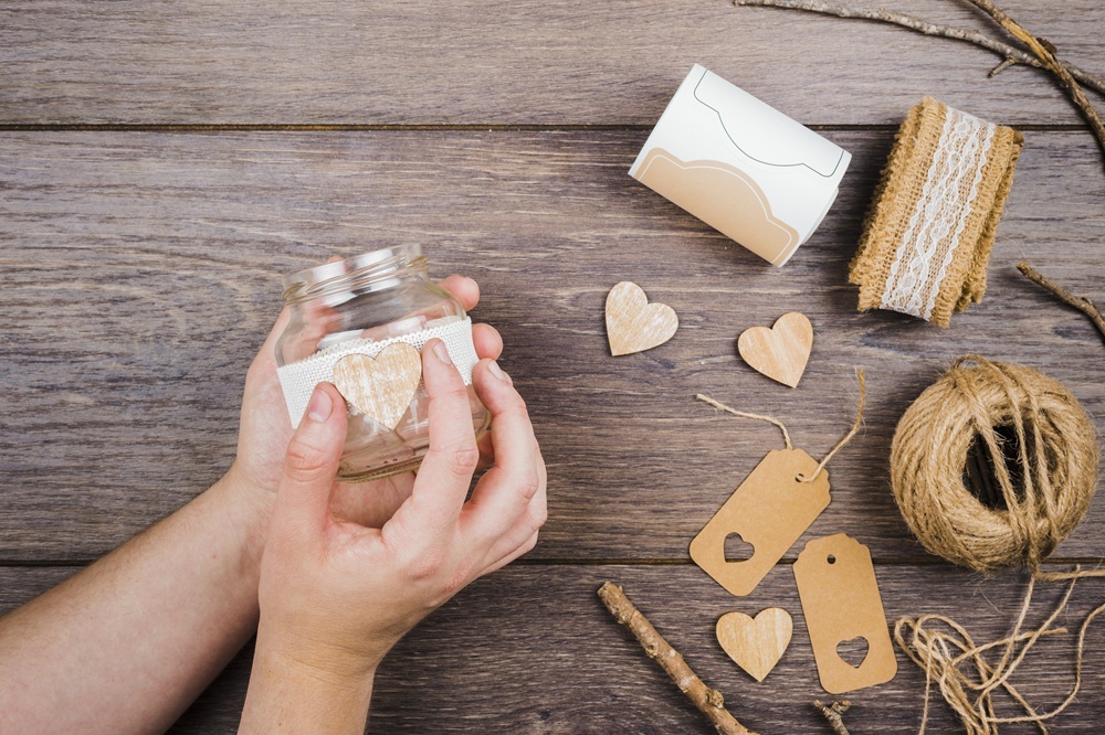Hands adding a wooden heart decoration to a glass jar