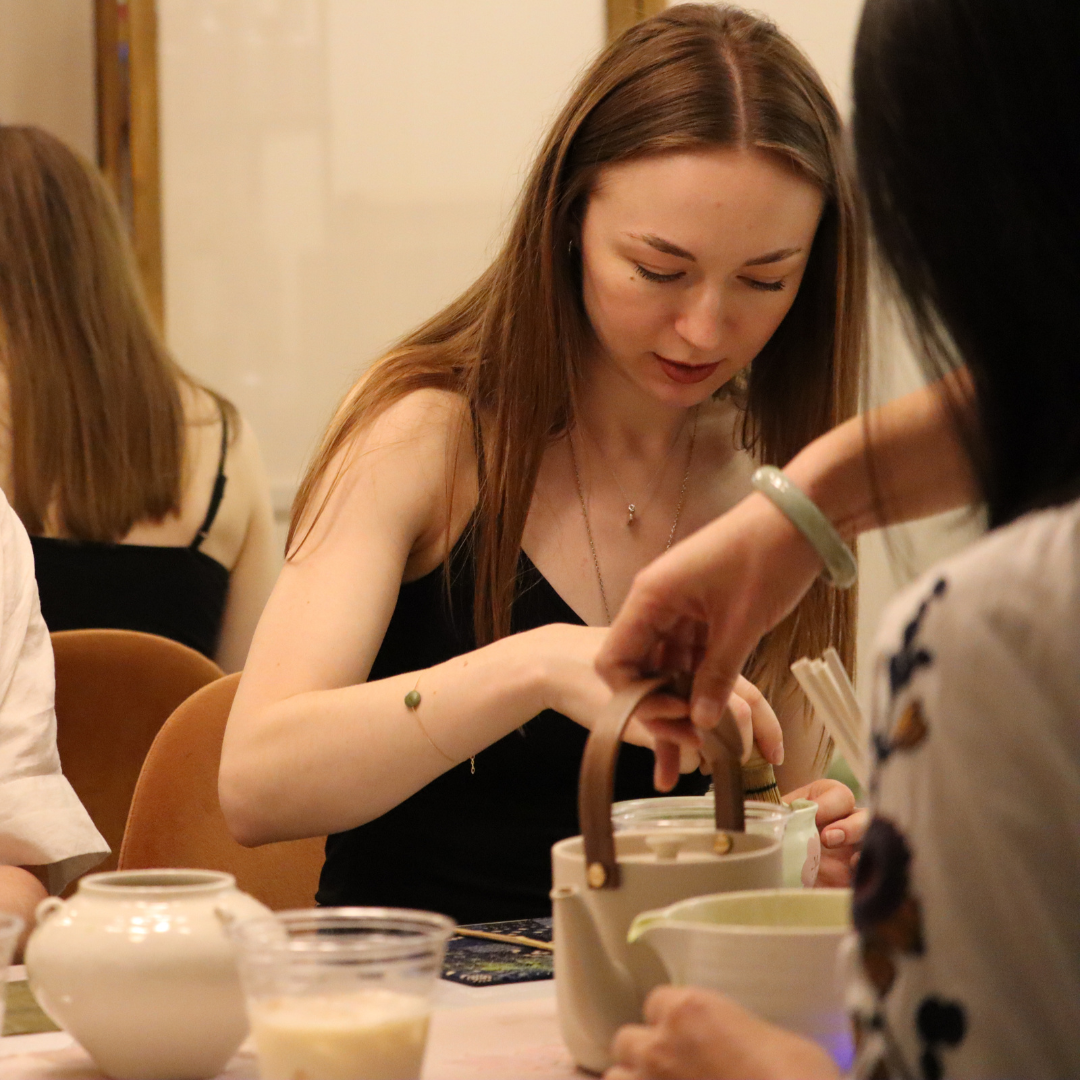 Young white woman attending a matcha workshop UK. Teaware and tea pot in the foreground