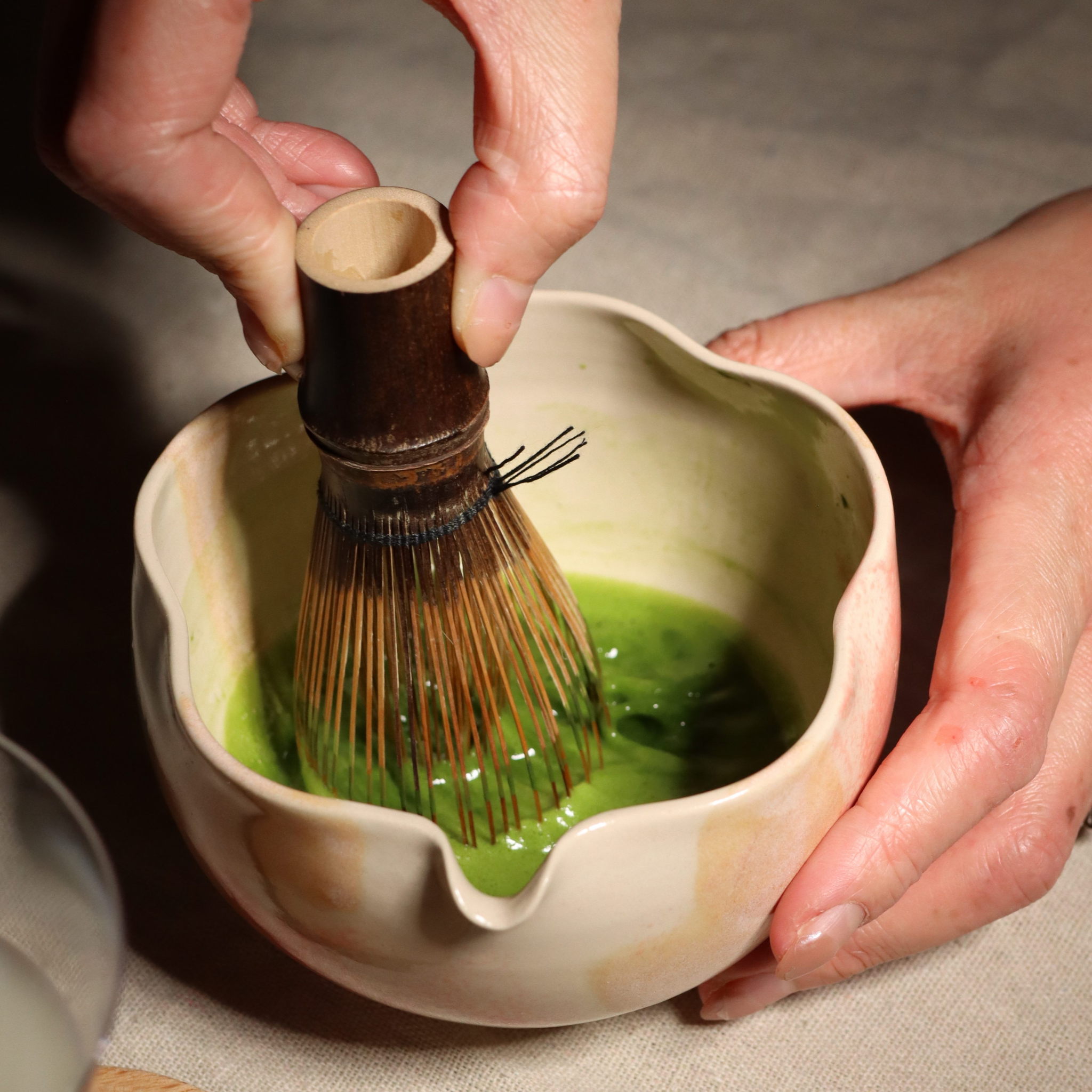 A bowl of bright green matcha tea with a whisk, representing the history of matcha from China to Japan.