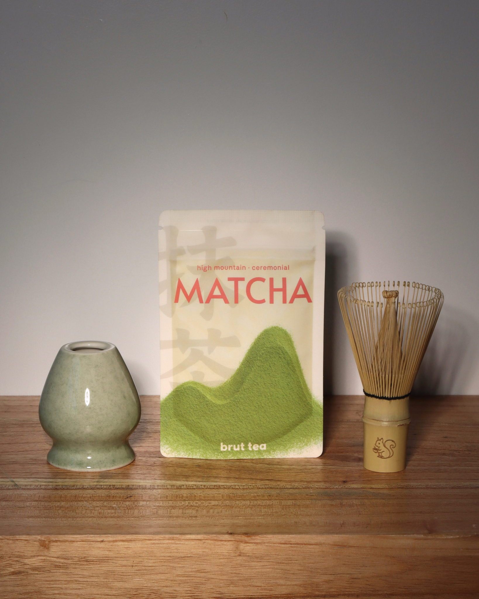 Matcha Starter Kit – ceramic jade coloured whisk stand on the left, brut tea high mountain ceremonial grade matcha 30g in the middle, kazuho white bamboo chasen matcha whisk on the right