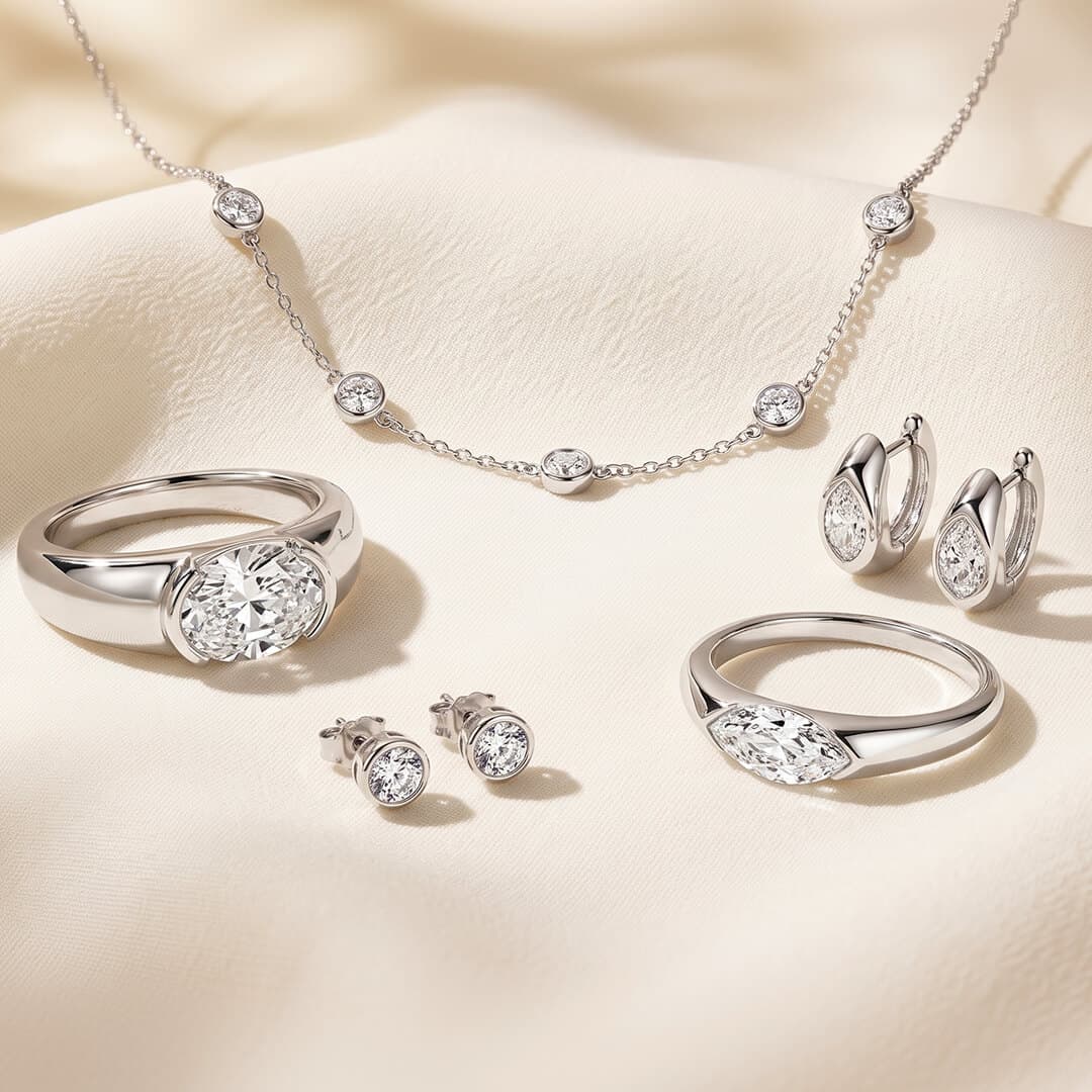 Bezel set moissanite jewelry collection featuring silver bezel rings, station necklace, and stud earrings