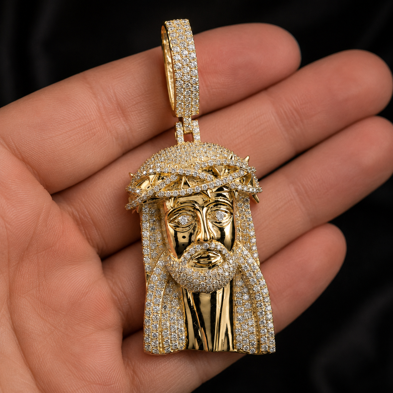 Hand holding gold iced out Jesus pendant with sparkling CZ stones