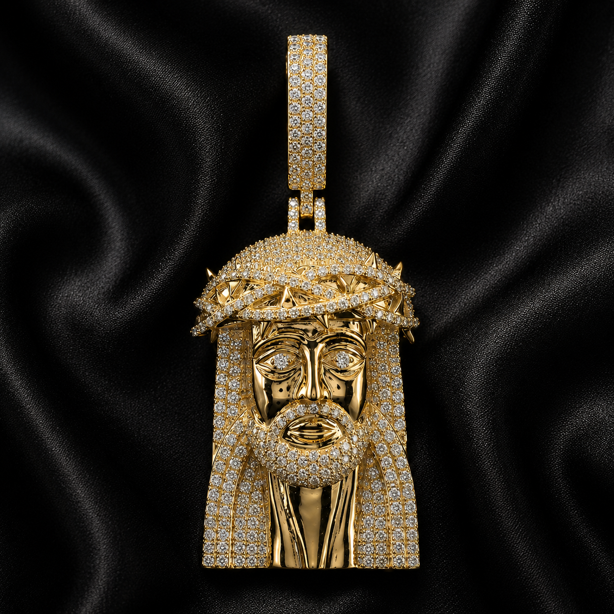Gold iced out Jesus pendant with thorn crown on black satin background
