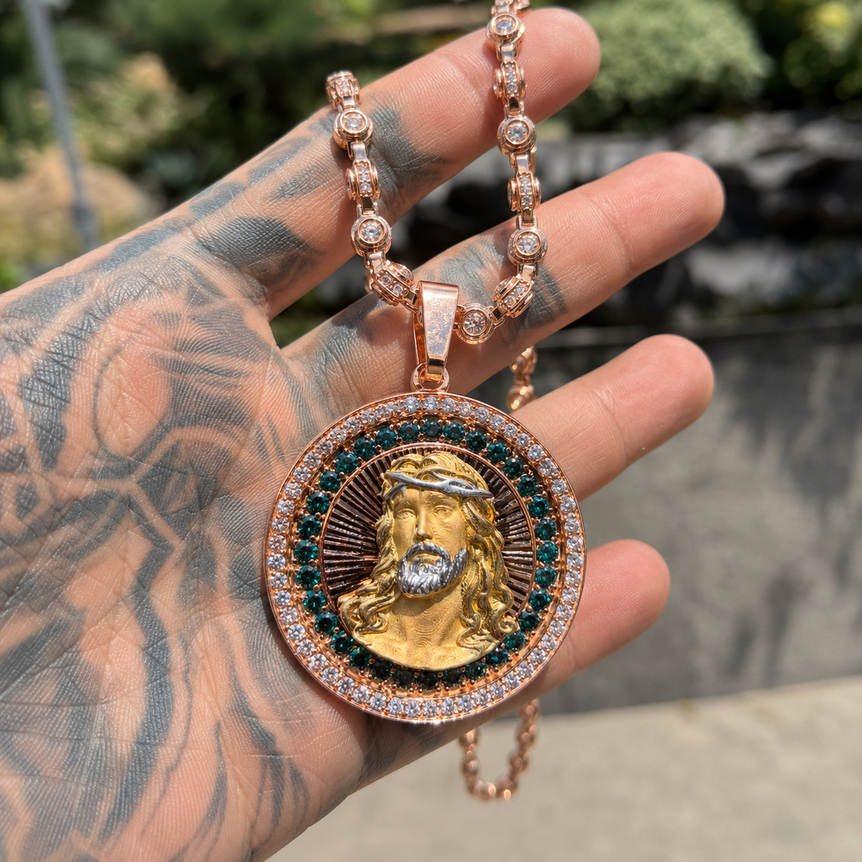 Hand holding gold iced out Jesus pendant with sparkling CZ stones