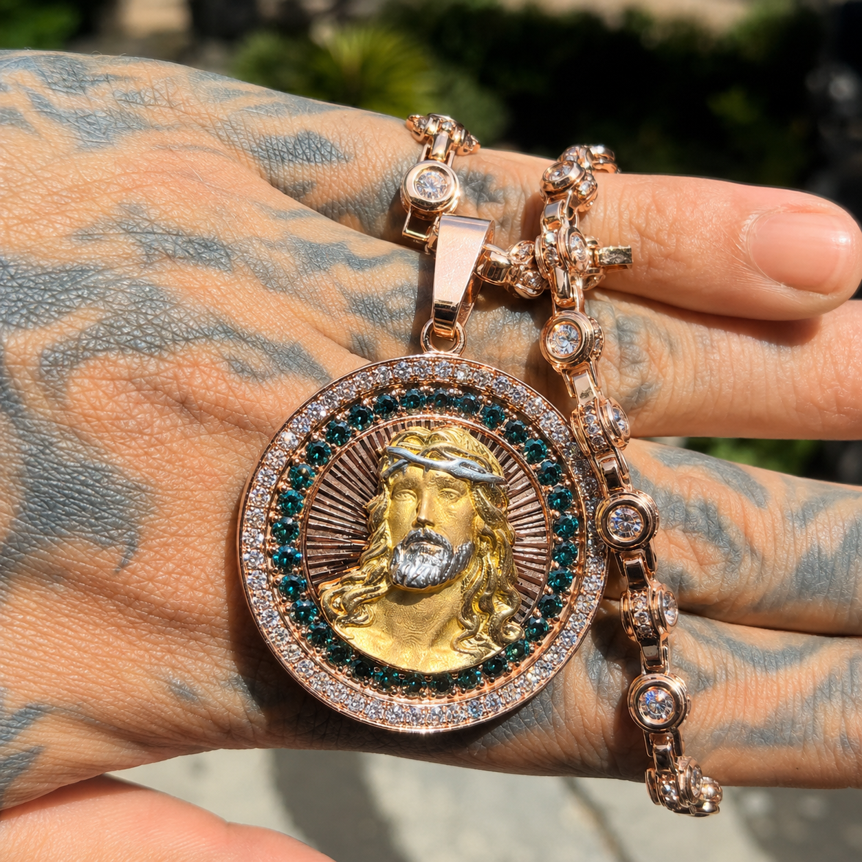 Hand holding gold iced out Jesus pendant with sparkling CZ stones