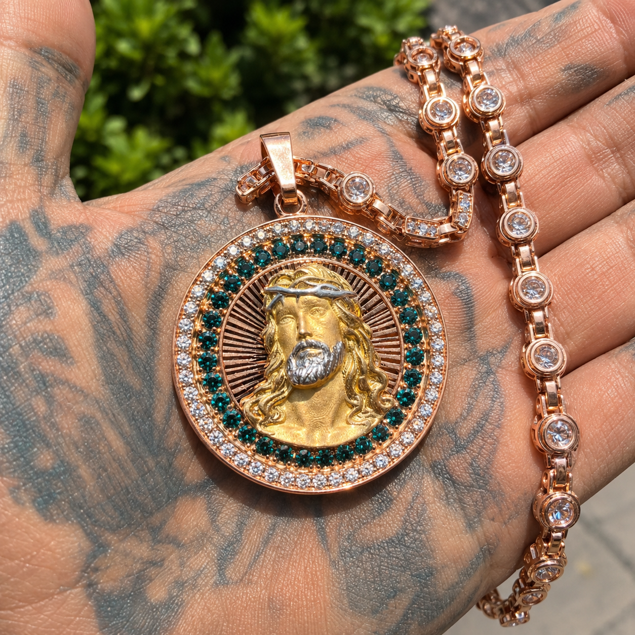Hand holding gold iced out Jesus pendant with sparkling CZ stones