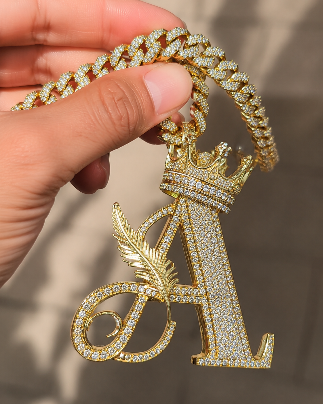 Gold Cuban chain with diamond-like Letter A pendant on hand