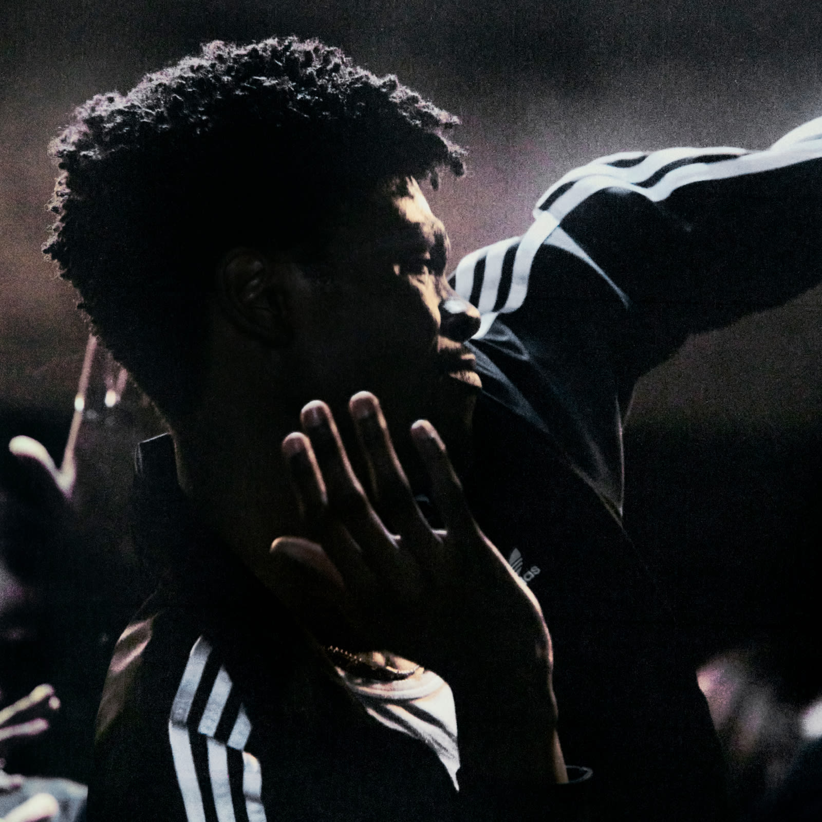 A person wearing an aditthhdas Firebird jacket with Three Stripes, dances against a dark background. 