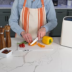 man slicing vegetables using the cutting board and one of the knives