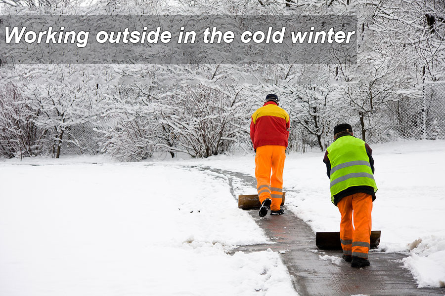 Worker braving a snowy, icy winter landscape while wearing protective gear, highlighting the importance of a worker-quality electric heated vest.