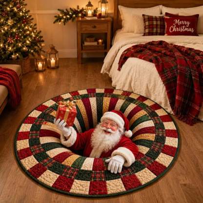 A round Christmas-themed rug with a patchwork design in red, green, and cream, featuring an embedded Santa Claus figure holding a gift. The rug is displayed on a wooden floor in a cozy, warmly lit bedroom setting with a bed, nightstand, and Christmas tree in the background.