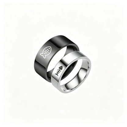Two interlocking stainless steel rings on a plain white background. The top ring is black with a white fish symbol, and the bottom ring is silver with a black fish skeleton symbol.