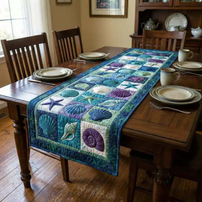 A quilted ocean themed table runner with shells and starfish squares on a dark wooden dining table in a cozy dining room with plates mugs and chairs