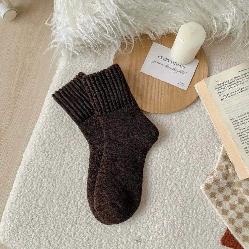 Brown sock on a textured surface with a candle and book in the background