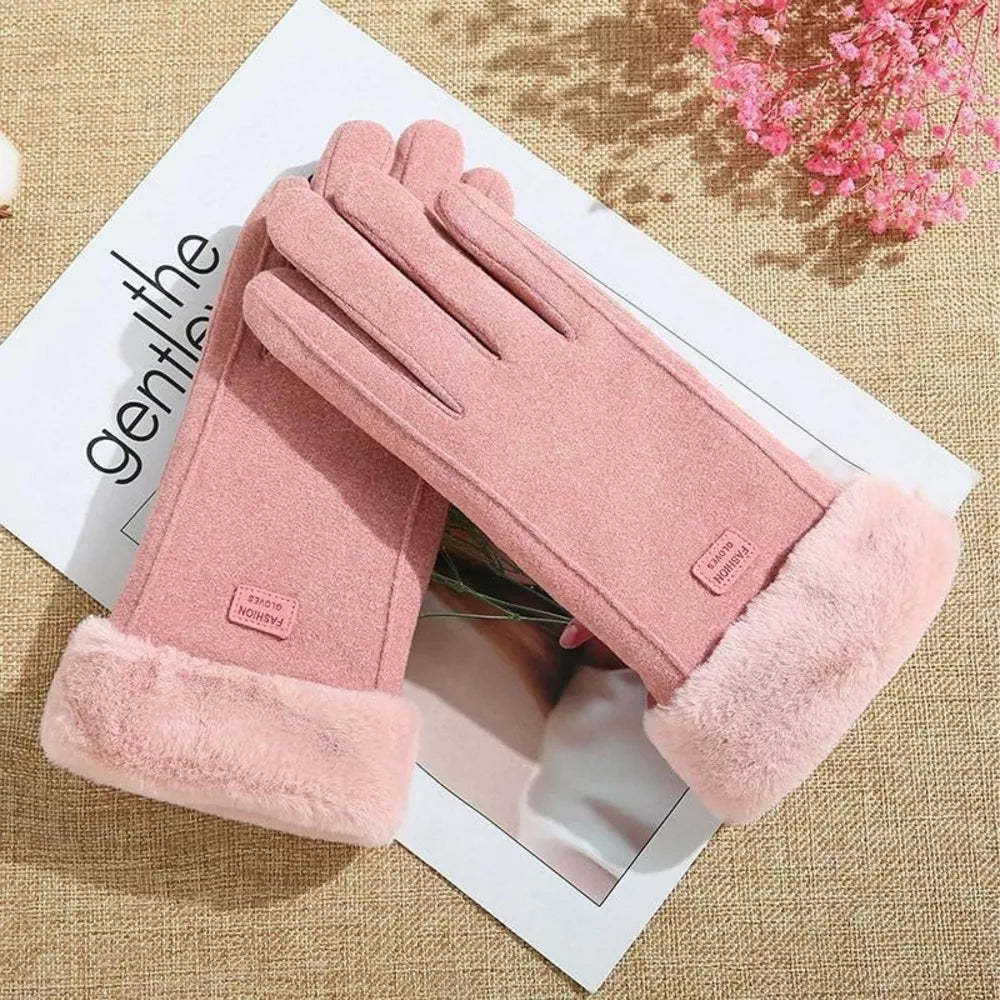 A pair of dusty pink winter gloves with plush faux-fur cuffs, arranged on a white printed card over a beige woven fabric.