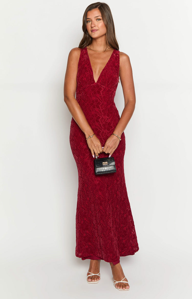 a blonde model a red maxi dress with black heels, gold bracelets and a black purse