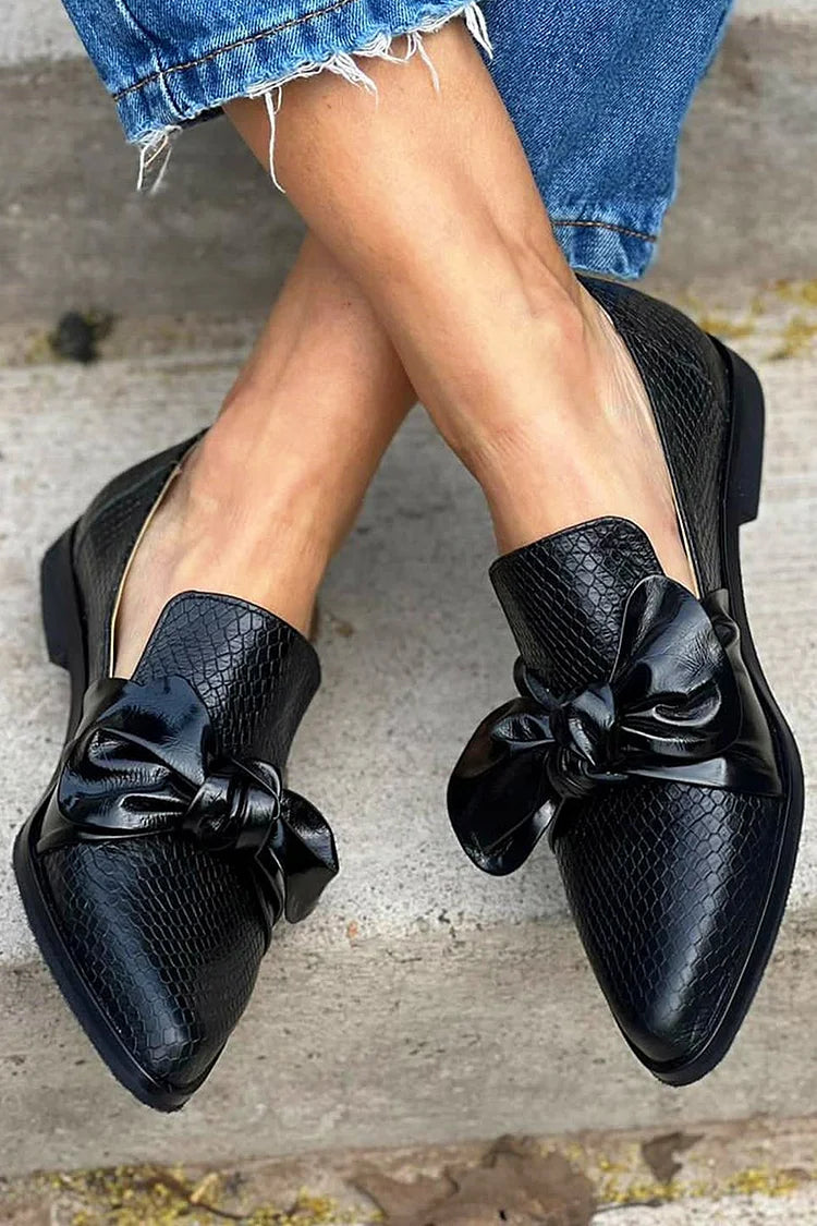 Black knotted pointed toe loafers with bow and snakeskin print