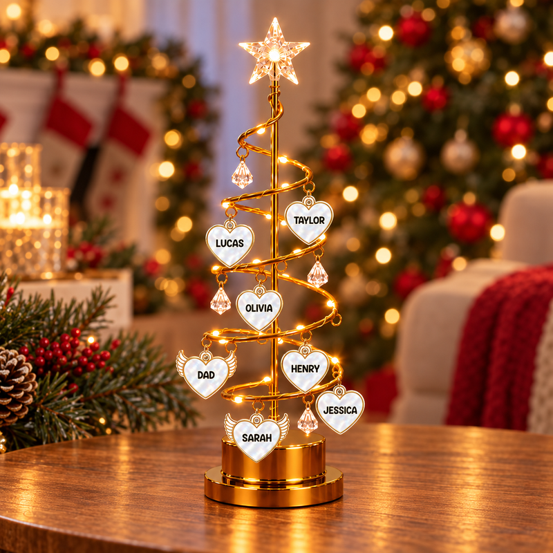 Christmas tree light with personalised heart and winged heart name charms on a wooden tabletop.