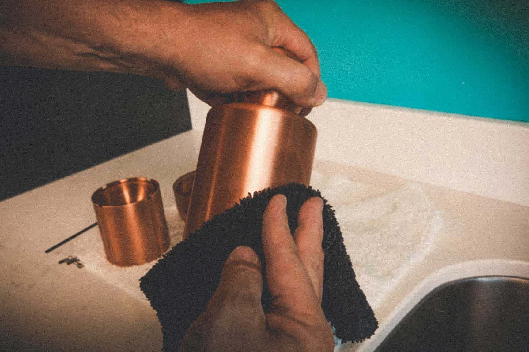 Man cleaning and polishing Meltdown Mini Mogul copper ice ball press.