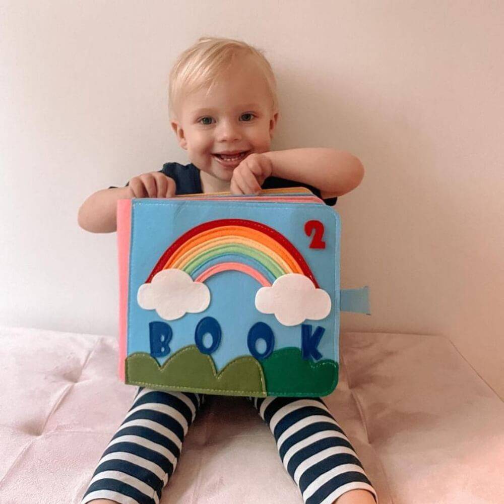 Little girl smiling while posing with her Montessori Story Book.