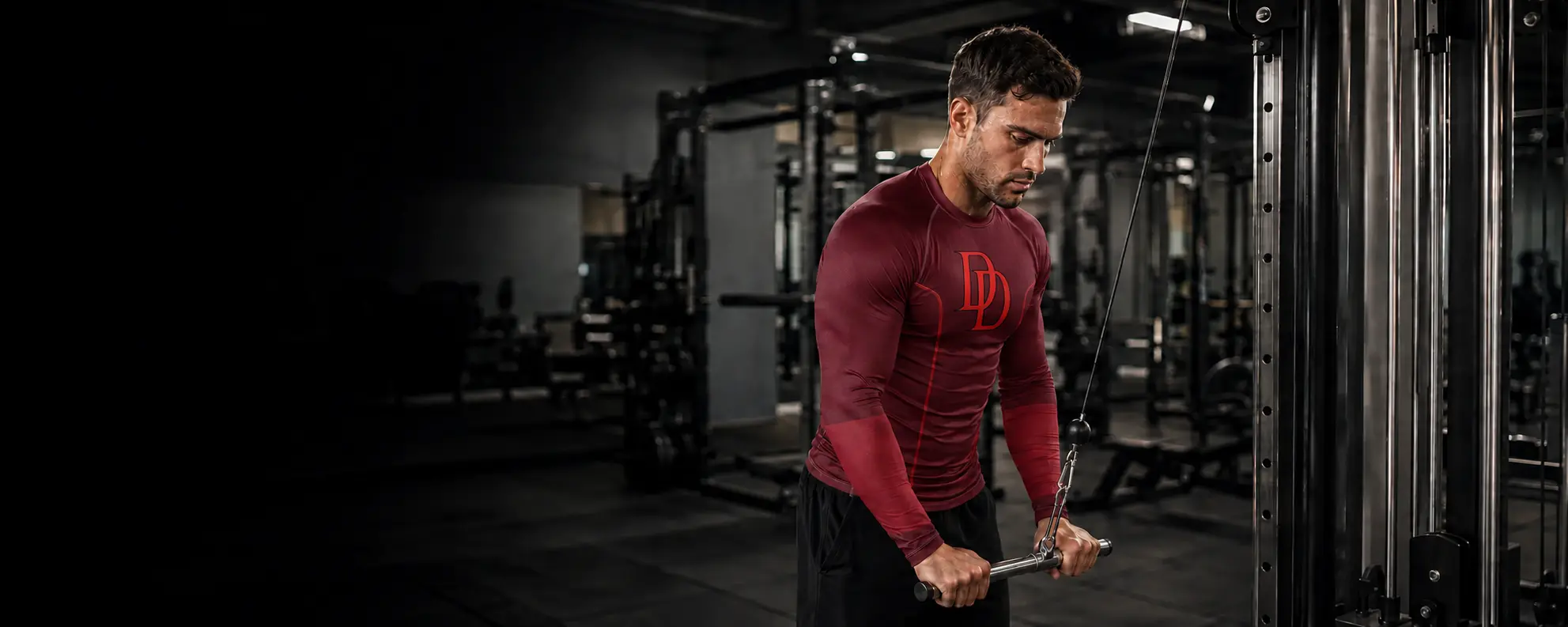 Athlete using a cable machine in a gym while wearing a burgundy DD long sleeve compression shirt