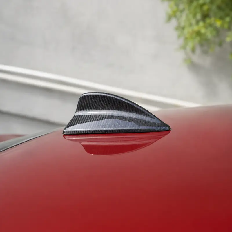 Real carbon fiber shark fin antenna cover installed on a red BMW roof