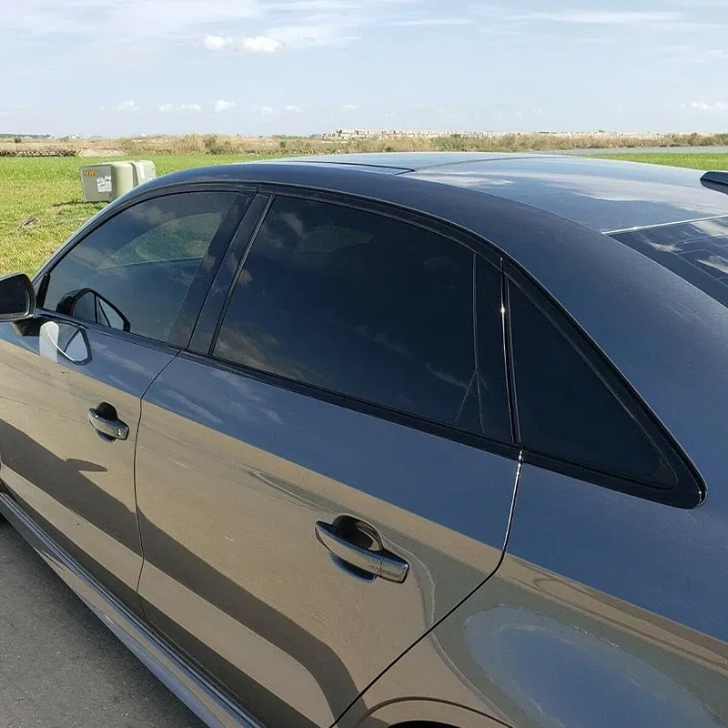 Side profile view of a grey Audi sedan featuring installed glossy black window trim chrome delete overlay on the rear doors and C-pillar