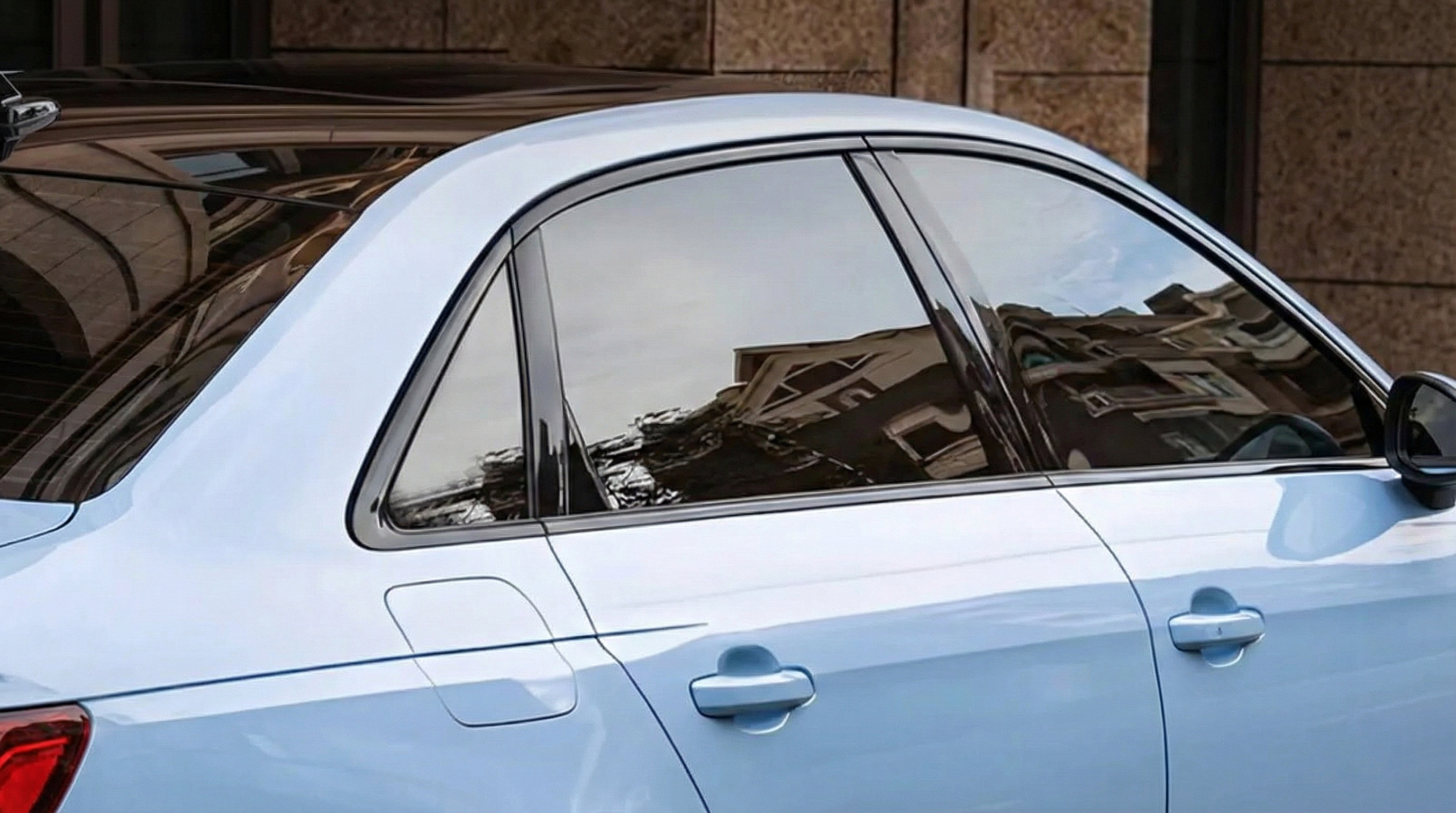 Close-up view of a light blue Audi sedan featuring glossy black window trim chrome delete on the rear windows and C-pillar.