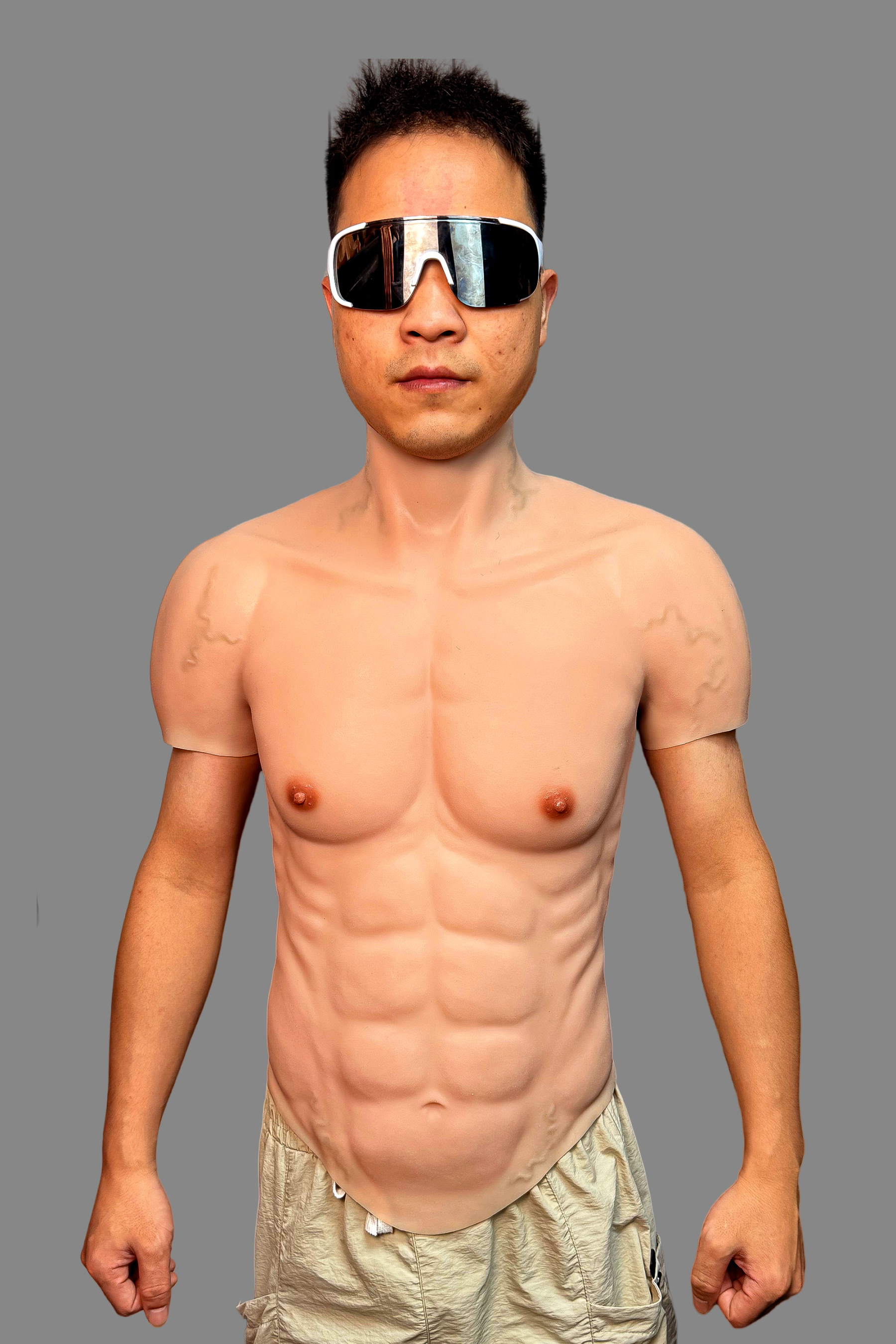 Realistic silicone muscle suit with defined abs, pecs and high collar neck, worn with oversized white sunglasses, side view.