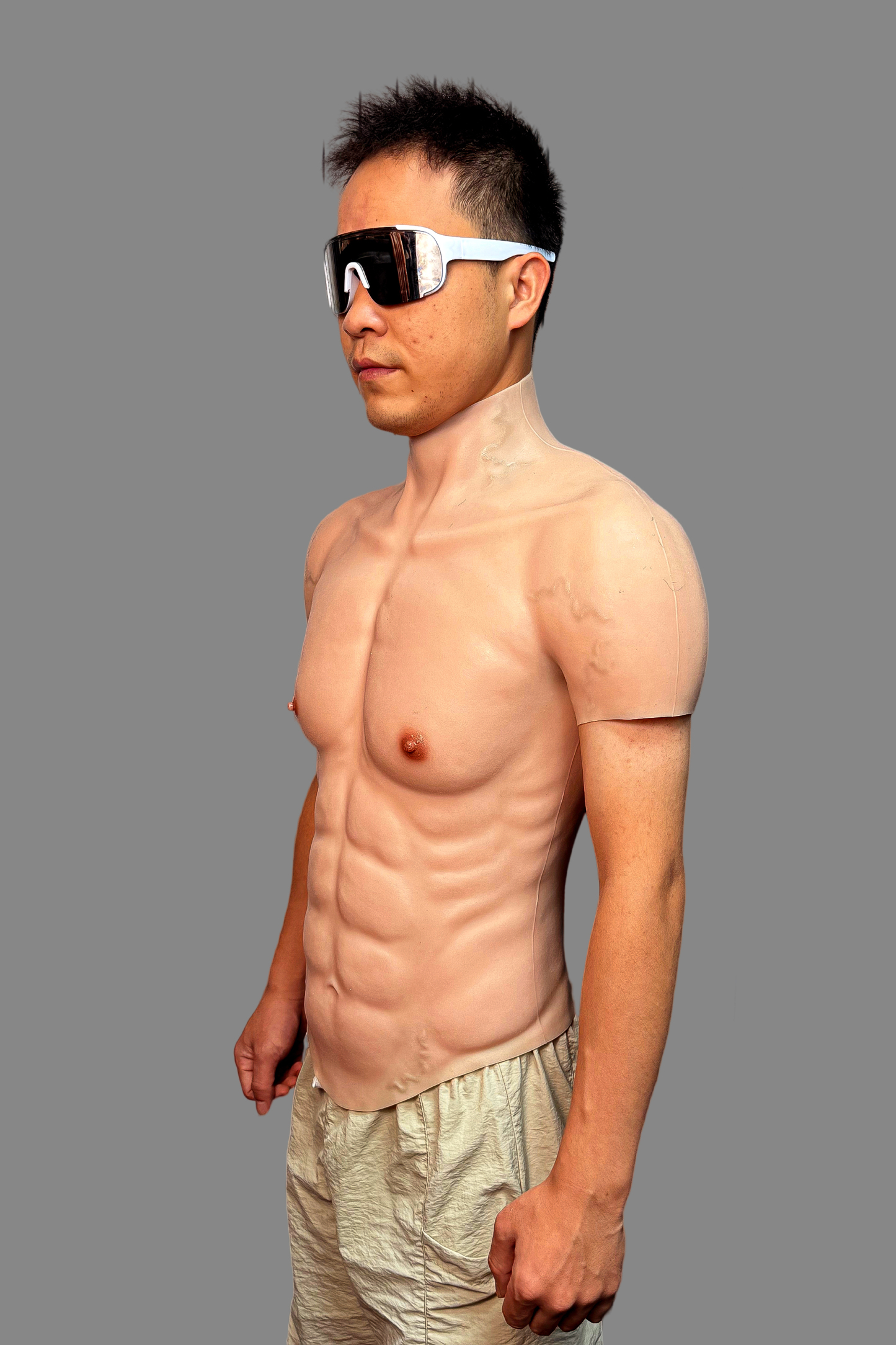 Ultra-lifelike muscular fake torso silicone suit with detailed abs, pectorals and vascular arms, front flexing pose with sunglasses