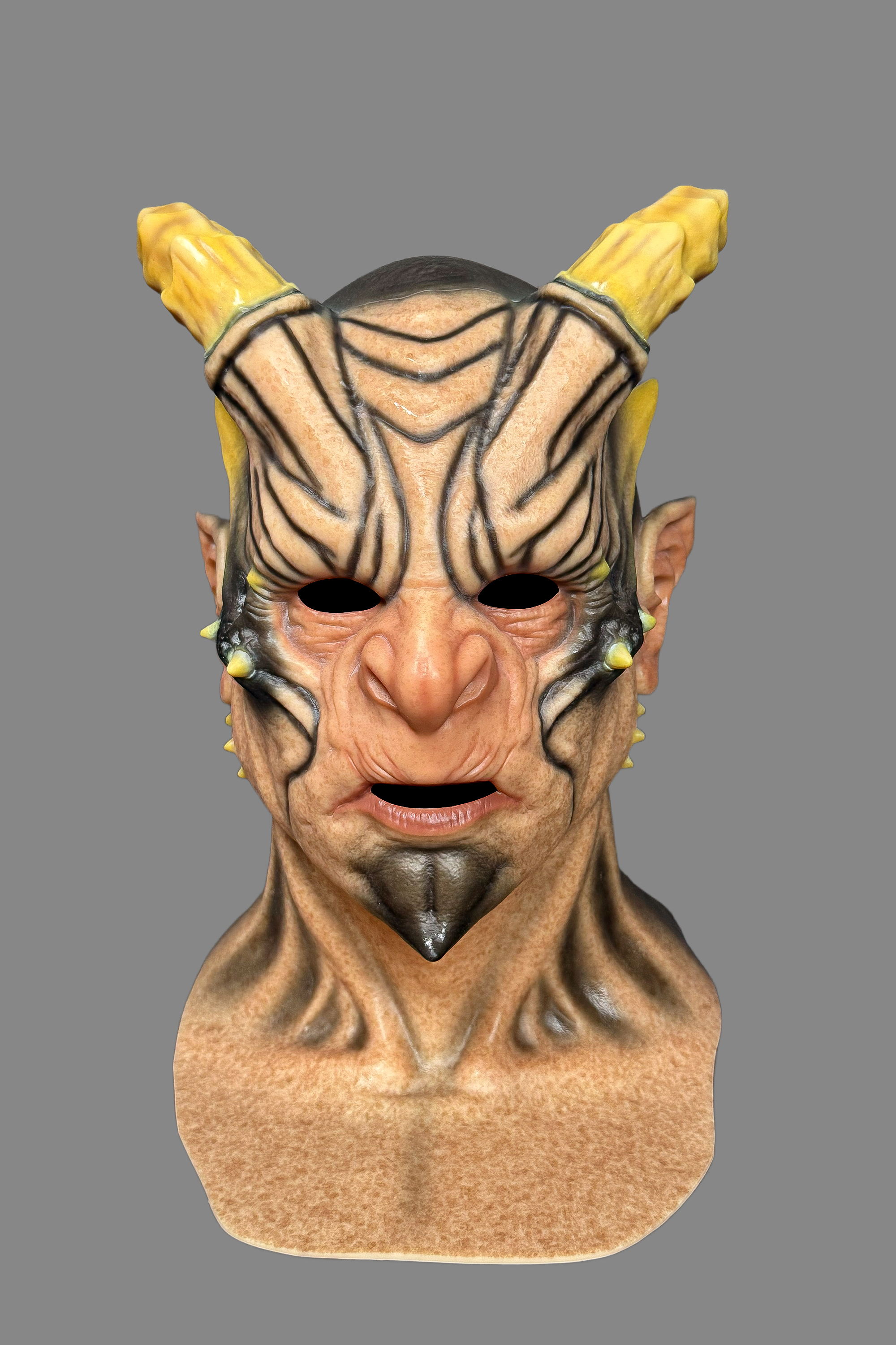 Terrifying horned demon Halloween silicone mask showing large curved yellow horns, pointed ears, tribal forehead design and realistic skin pores, right side view.