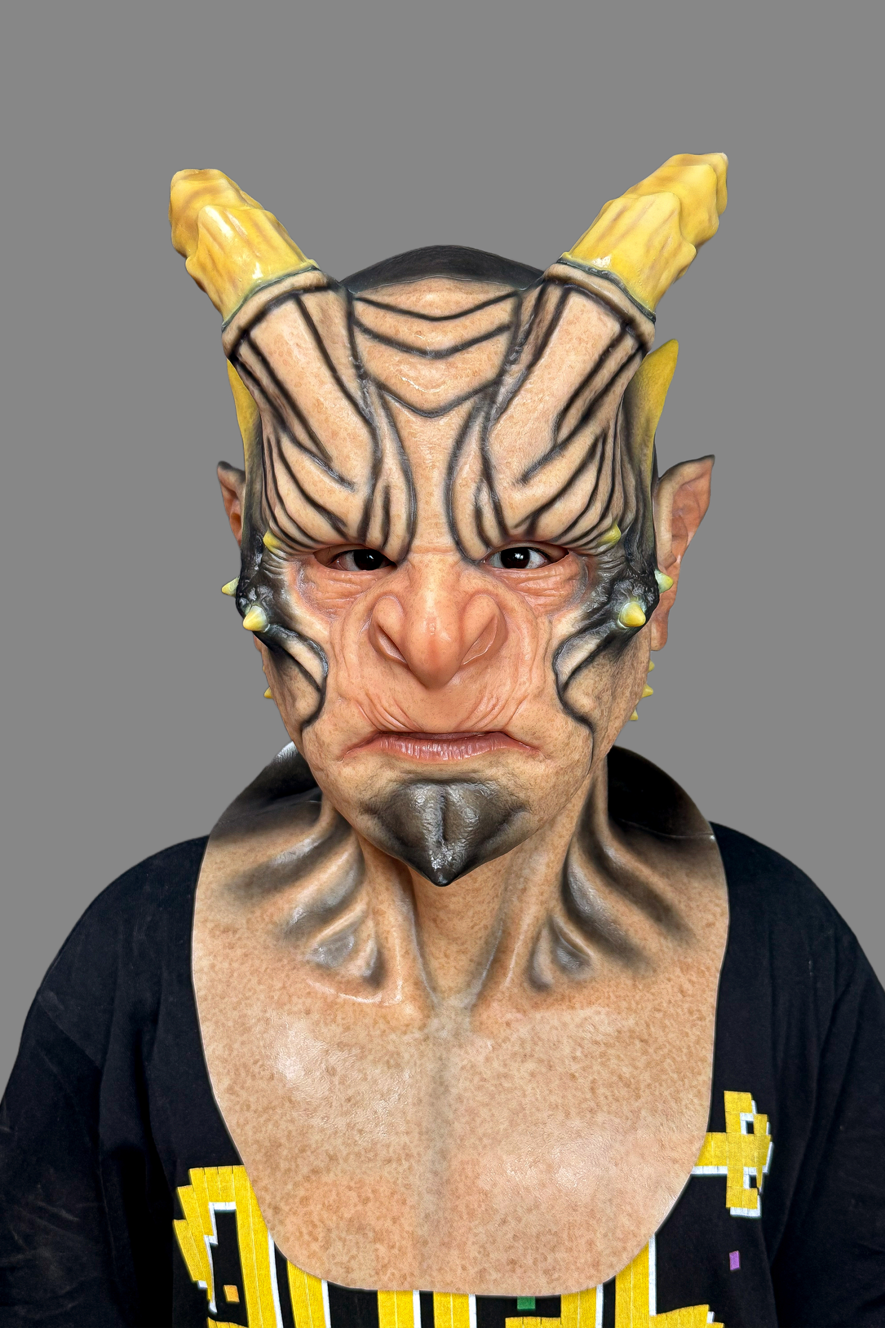 Hyper-realistic demon devil silicone mask with large yellow curved horns, tribal forehead markings, pointed ears and spiked chin, three-quarter angle display.