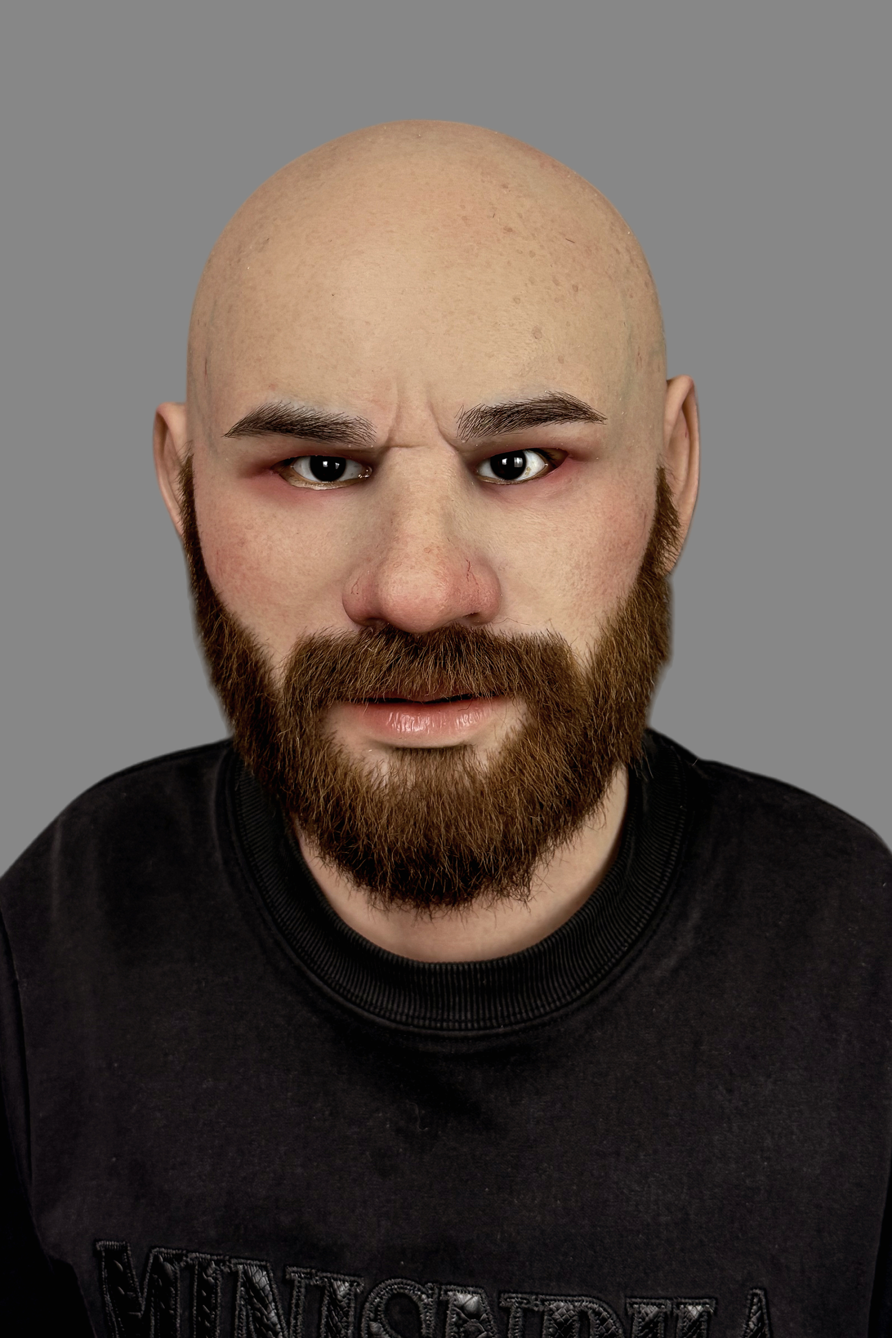Hyper-realistic bald bearded man silicone mask with full bushy beard, realistic skin pores and angry expression, front view worn on model.