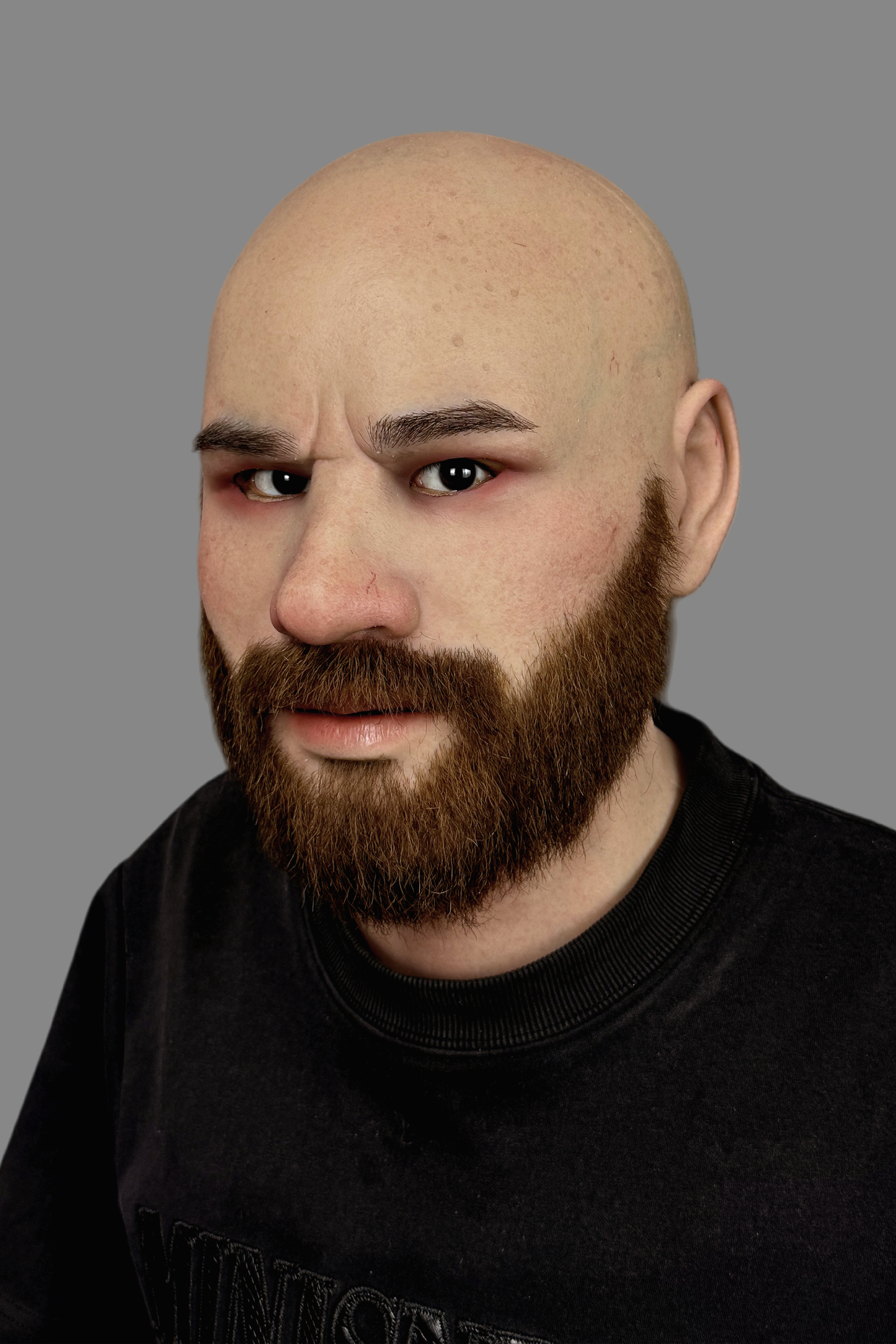 Ultra-lifelike bald male silicone disguise mask with thick real human hair beard and detailed ear, left side view.