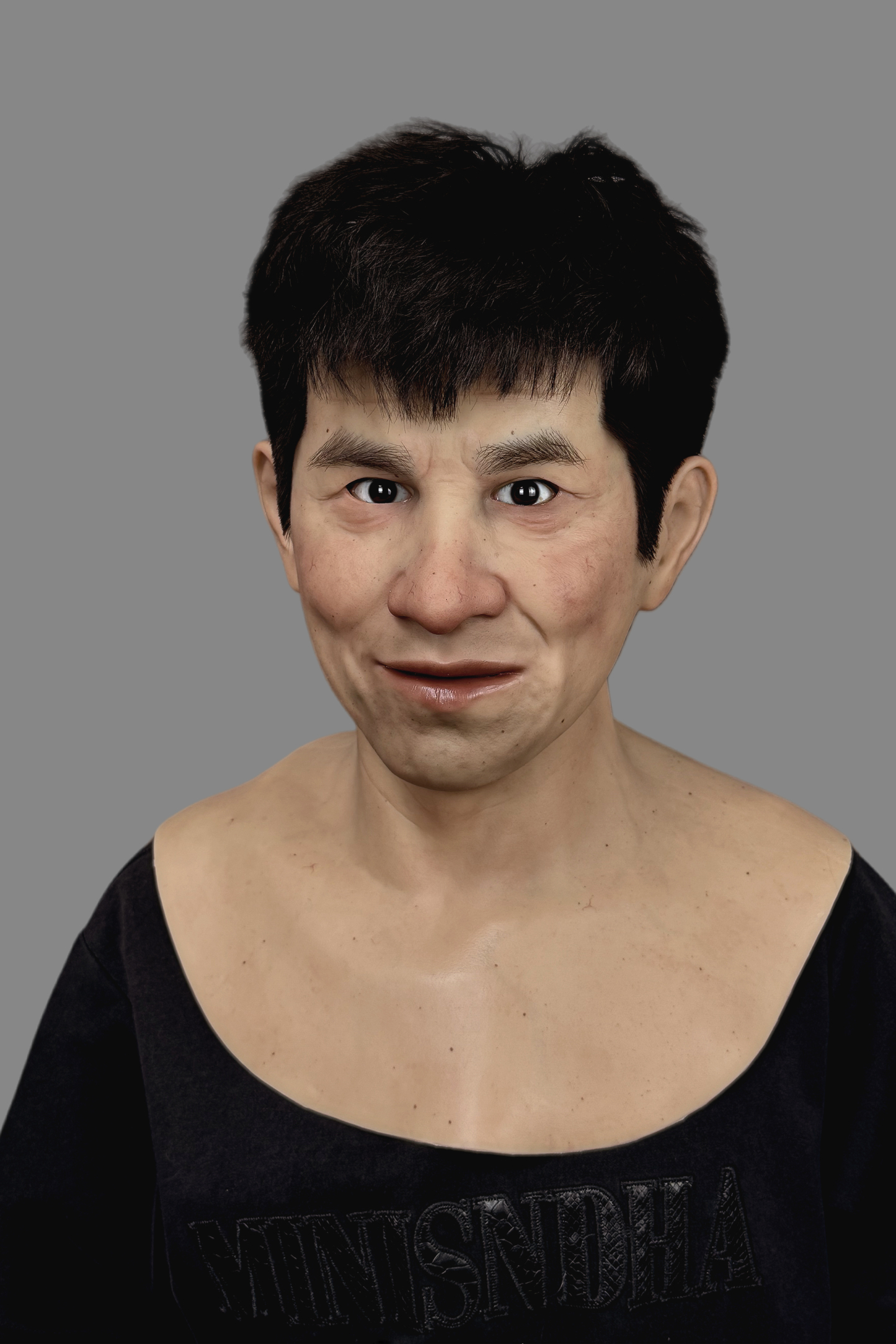 Hyper-realistic  male silicone mask with short black hair and subtle smirk, detailed skin pores and neck blend, left side view.