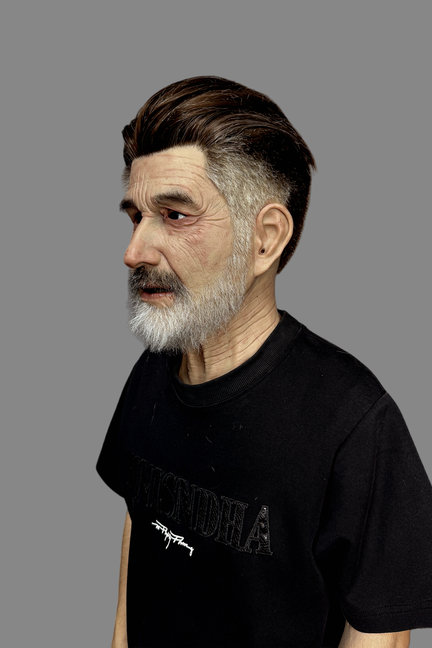 Premium hyper-realistic senior male silicone mask with dark brown slicked-back hair, white beard, subtle smile and lifelike pores, worn on model.