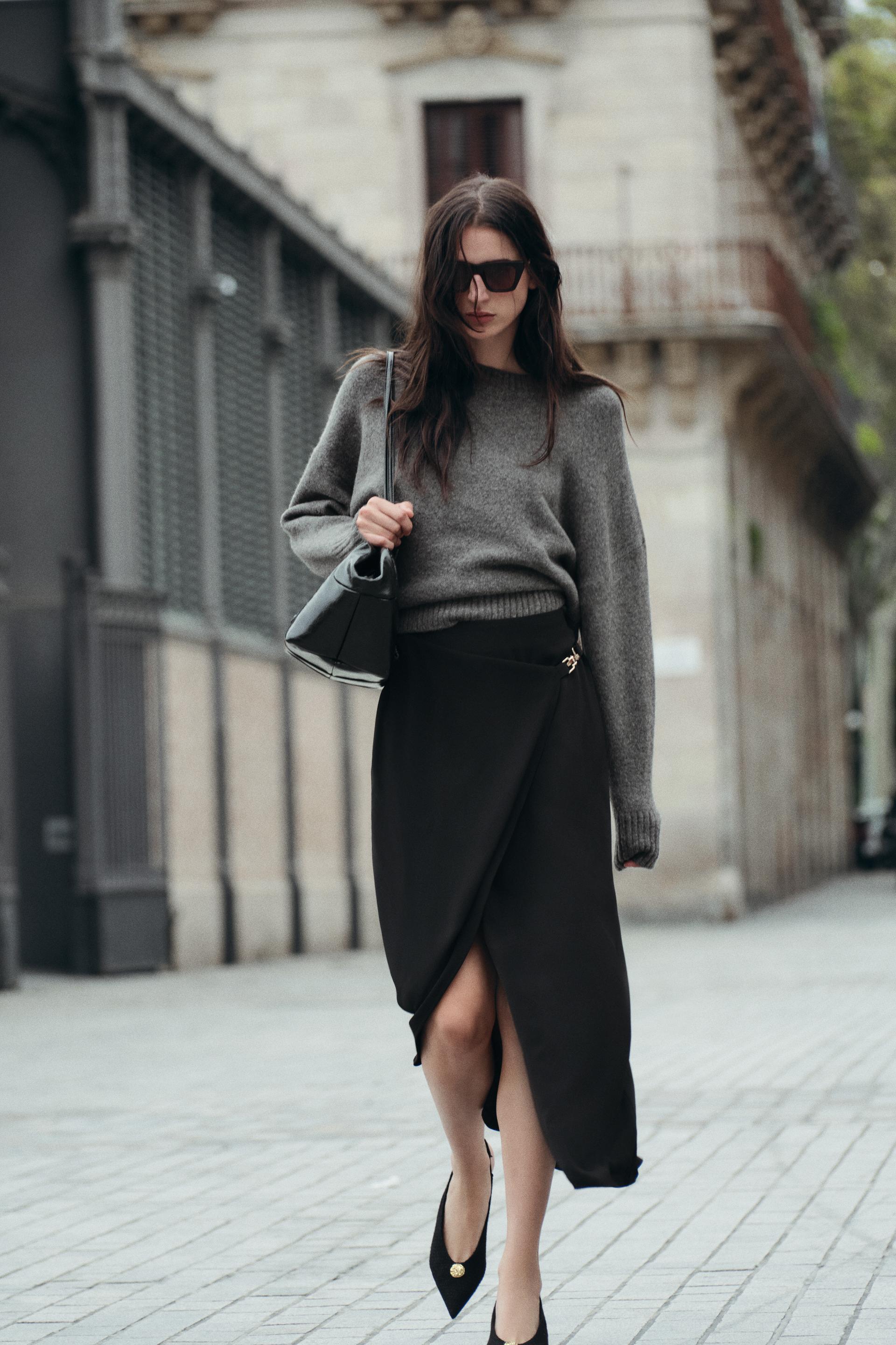 High waisted skirt with front slit. Wrap closure with hidden interior button and golden clip appliqu.