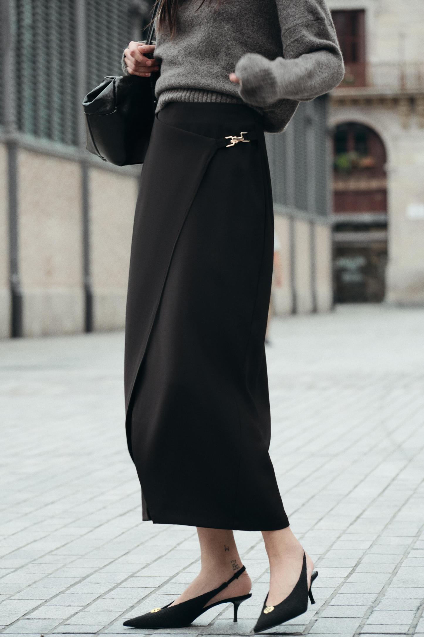 High waisted skirt with front slit. Wrap closure with hidden interior button and golden clip appliqu.