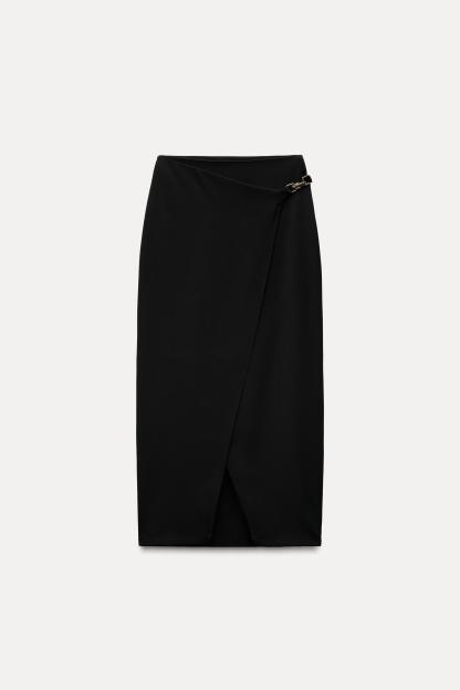 High waisted skirt with front slit. Wrap closure with hidden interior button and golden clip appliqu.