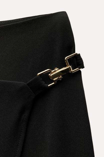 High waisted skirt with front slit. Wrap closure with hidden interior button and golden clip appliqu.