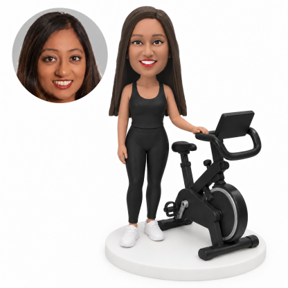 custom bobblehead figure fitness woman standing beside a stationary exercise bike